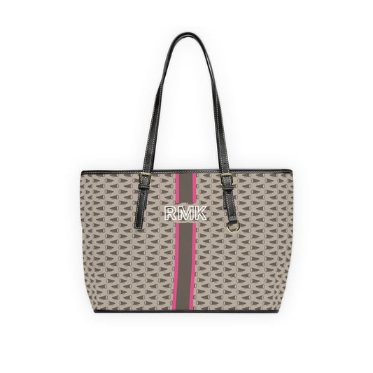 A structured tote bag featuring a beige and brown geometric megaphone monogram pattern, a vertical teal stripe down the center, and a white monogram printed on the front. The bag has black faux-leather shoulder straps and trim, shown against a plain white background.