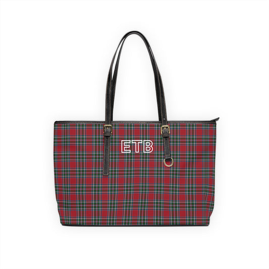 A red and green tartan plaid tote bag with black faux-leather shoulder straps and a white outline monogram on the front.