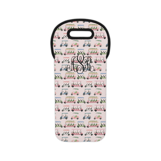 A neoprene wine bag featuring a repeating pattern of golf carts in green, pink, and blue on a light pink background, with a black 3-initial monogram overlay in the center.
