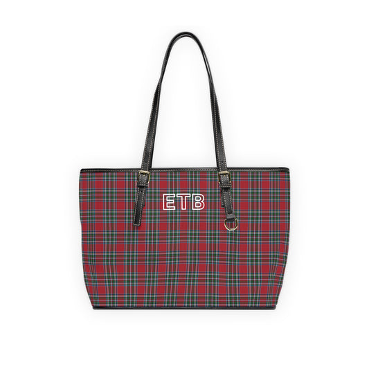 A red and green tartan plaid tote bag with black faux-leather shoulder straps and a white outline monogram on the front.